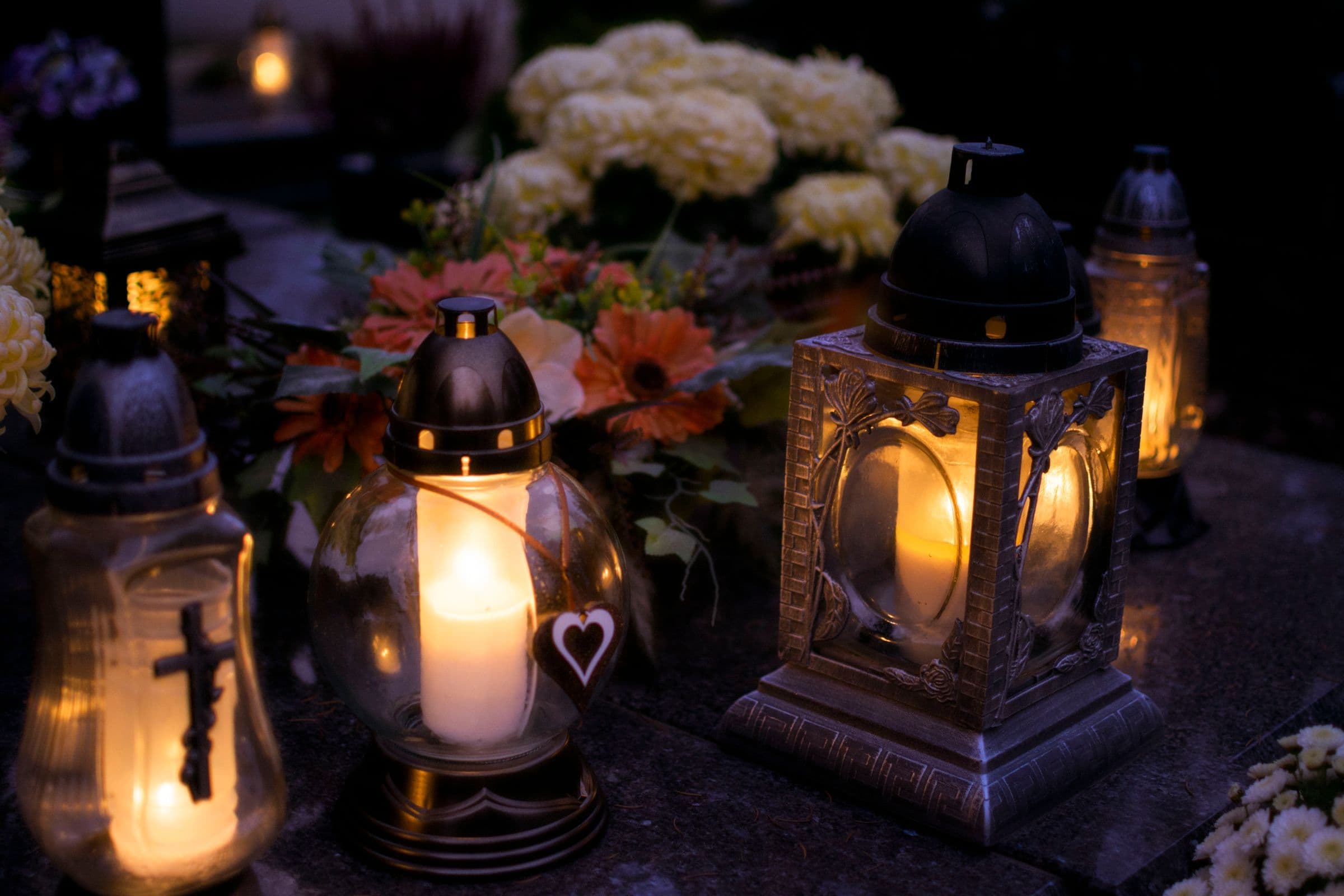 Glowing memorial lanterns and flowers in a cemetery on All Saints’ Day.