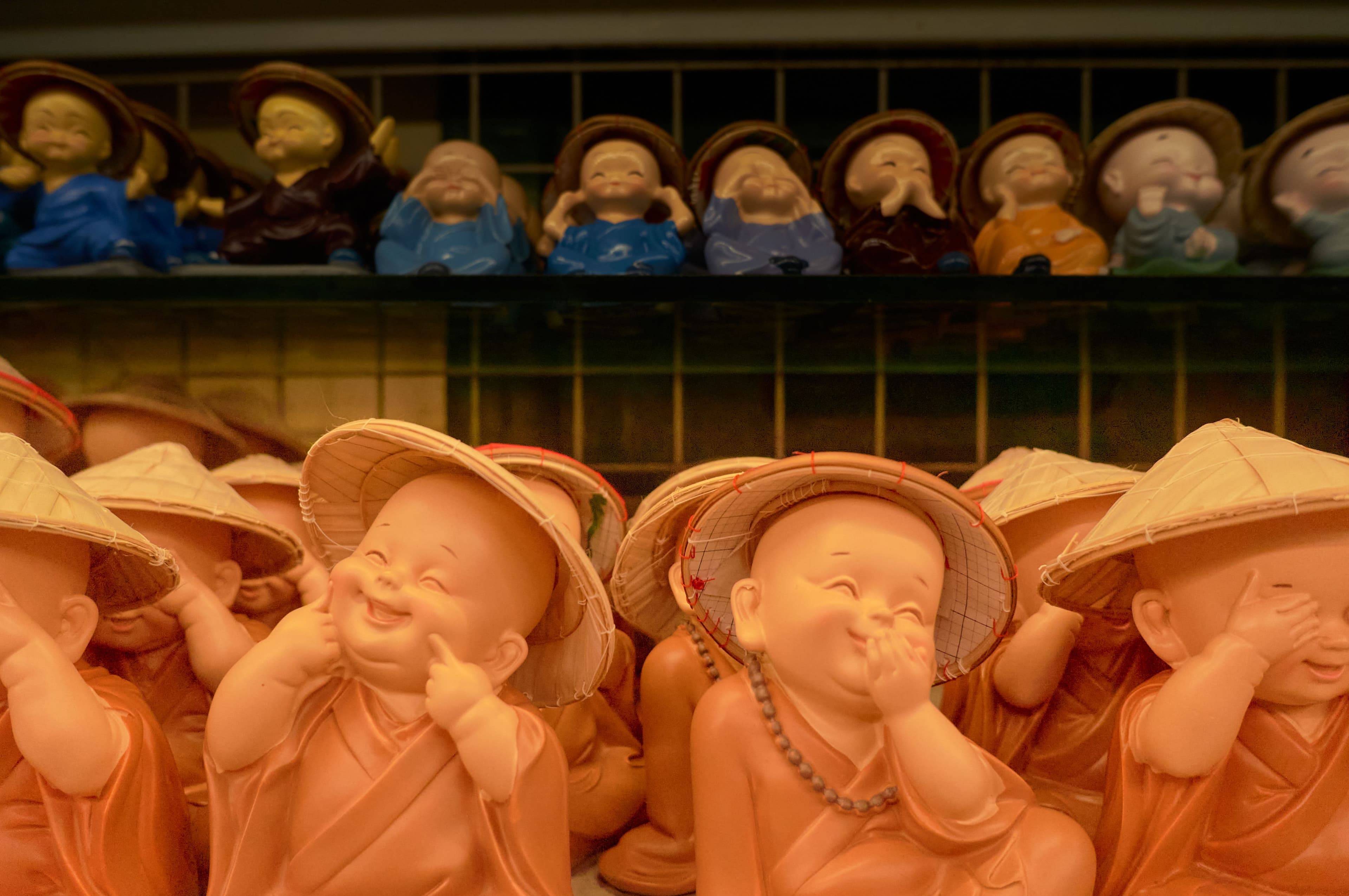 Smiling decorative monk statues wearing traditional attire and hats.